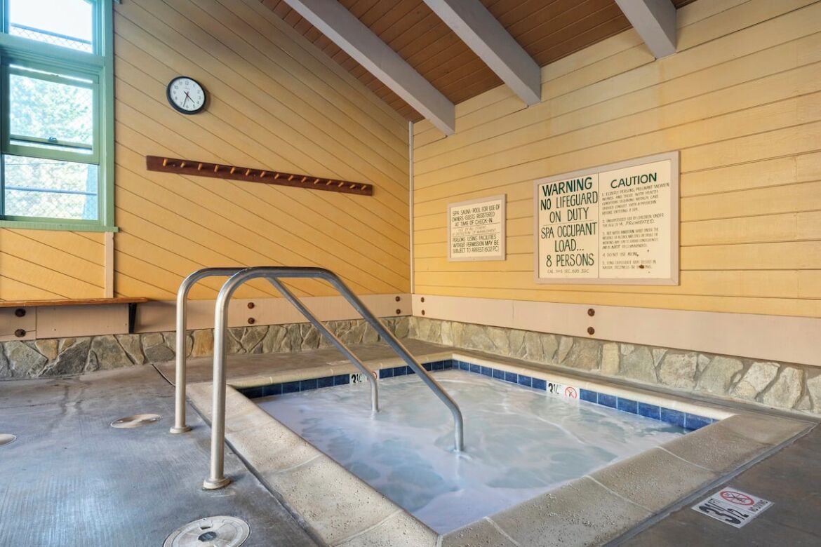 Un jacuzzi con escalones metálicos y carteles de advertencia en la pared.