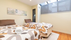 Ein Schlafzimmer mit zwei Betten, einem großen Fenster und einem Bild an der Wand.