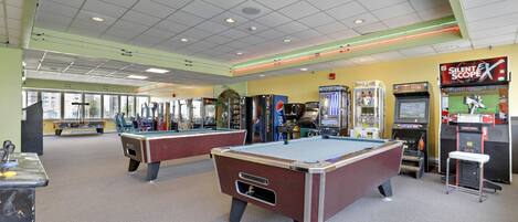 A recreational area with pool tables, arcade games, and vending machines.