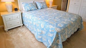 Een slaapkamer met een bed, twee nachtkastjes, een wanddecoratie en een deur.
