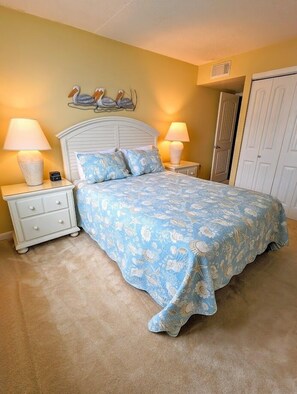 A bedroom with a bed, two nightstands, a wall decoration, and a door.
