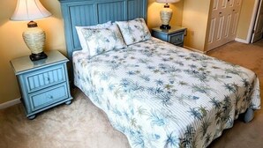 Een slaapkamer met een bed, twee nachtkastjes, twee lampen, een hoofdbord en een deur.