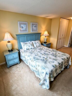 A bedroom with a bed, two nightstands, two lamps, a headboard, and a door.