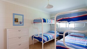 Une chambre de dortoir avec des lits superposés, une commode et un miroir.