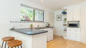 Una cocina moderna con armarios blancos, encimera de granito, microondas integrado y ventana con vistas al verdor.