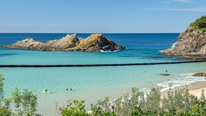 A coastal beach with clear turquoise waters, rocky formations, and a sandy shore. - Sea Shack - at Seal Rocks (Seal Rocks)