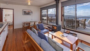 A cozy interior with a dining area, seating, and a large window overlooking a scenic view.
