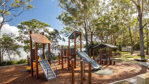 Ein Spielplatz mit Rutsche, Klettergerüsten und einer kleinen Schutzhütte.