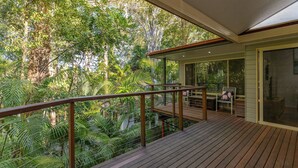 Eine Holzterrasse mit Geländer, die auf einen üppigen Garten blickt.