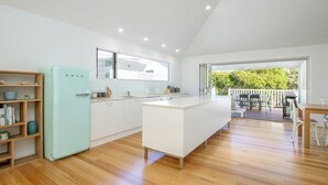 A modern kitchen with white cabinetry, a light blue refrigerator, and a large island. - Banksia - Pacific Palms Holidays (Blueys Beach)