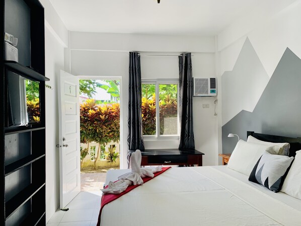 Un dormitorio con cama, escritorio y aire acondicionado.
