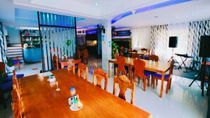 Un comedor moderno con una mesa de madera larga, varias sillas y una cocina al fondo.