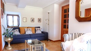 Una sala de estar con sofá, sillón y lámpara de pie.