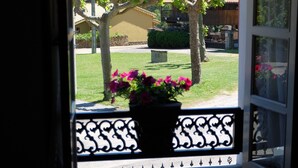 Una ventana con vista a un jardín, un banco y una planta en maceta con flores.