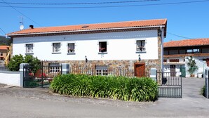Un edificio de dos pisos con tejado de tejas, fachada de piedra y entrada porticada.