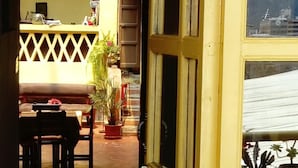 Una porta oberta que dona a una habitació amb terra de fusta, una taula, cadires i una planta en test.
