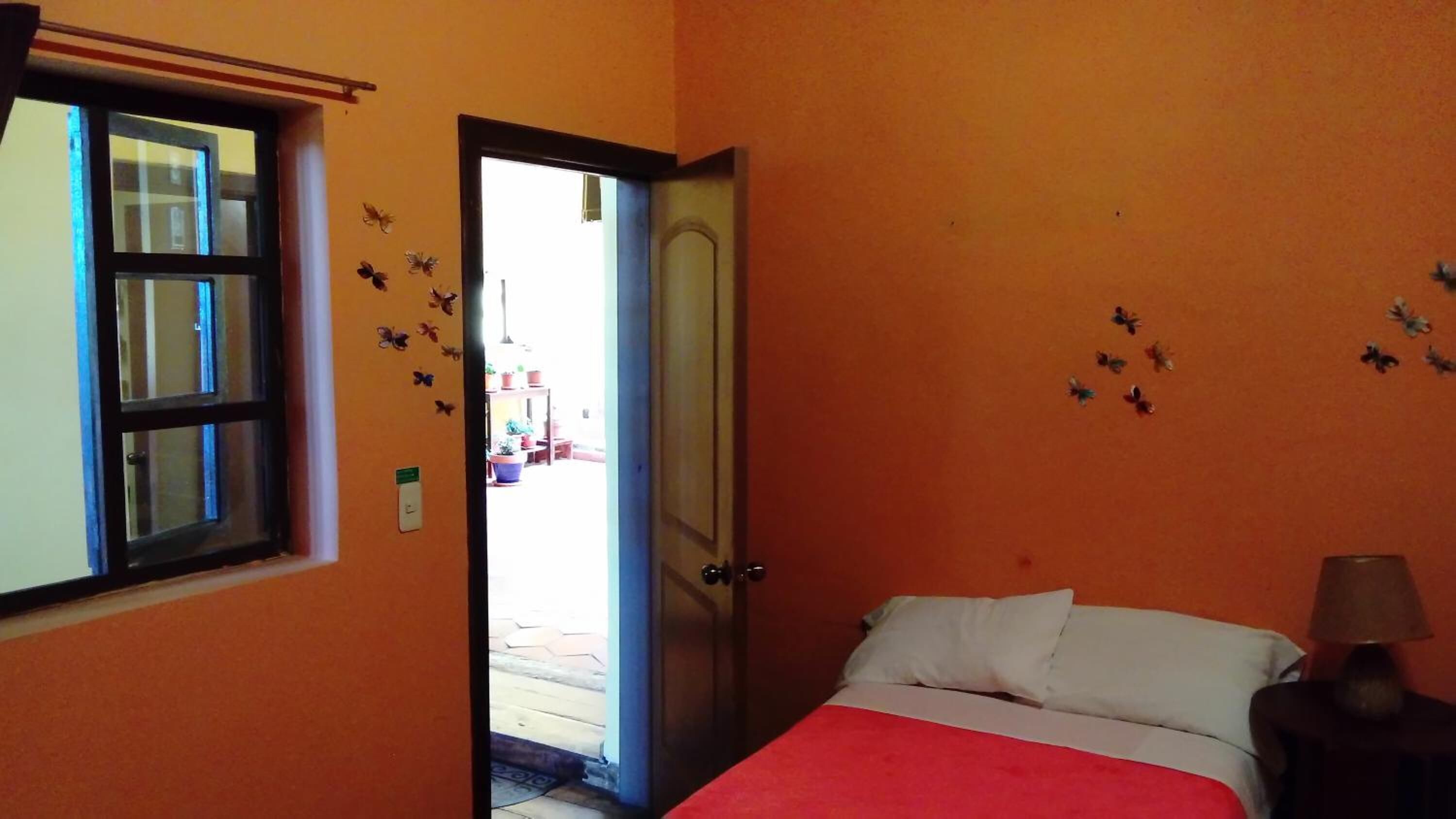 A room with a bed, a nightstand, a window, and a door leading to an outdoor area.