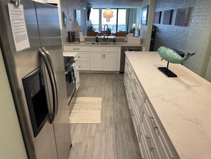 A modern kitchen with stainless steel appliances, white cabinetry, and a marble countertop. - Aransas Princess #203 - 2BR, 2BA Bright Ocean View Condo (Port Aransas)