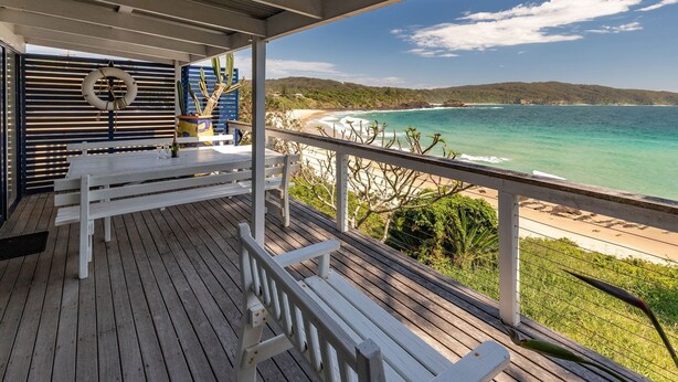 A wooden deck with white benches and a lifebuoy, overlooking a beach and ocean. - The Shack - at Seal Rocks (Seal Rocks)