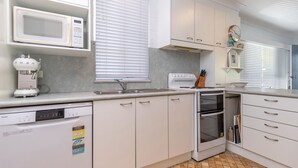 Una cucina moderna con mobili bianchi, forno a microonde integrato, lavastoviglie e forno.