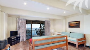 Quarto com cama, televisão e vista para o mar.