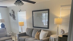 Una sala de estar con un sofá modular, una mesita, una lámpara y un ventilador de techo.