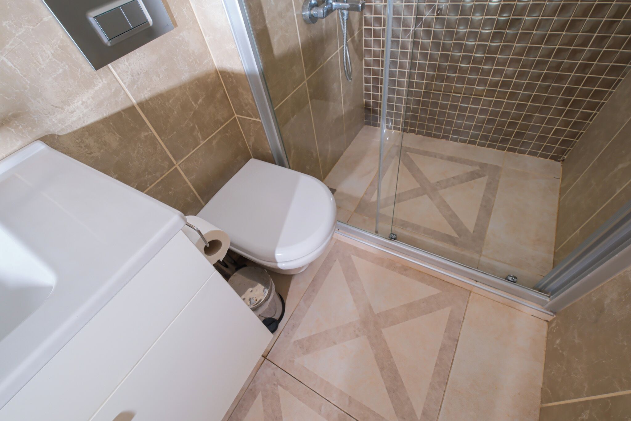 A bathroom with a toilet, shower, and tiled floor.