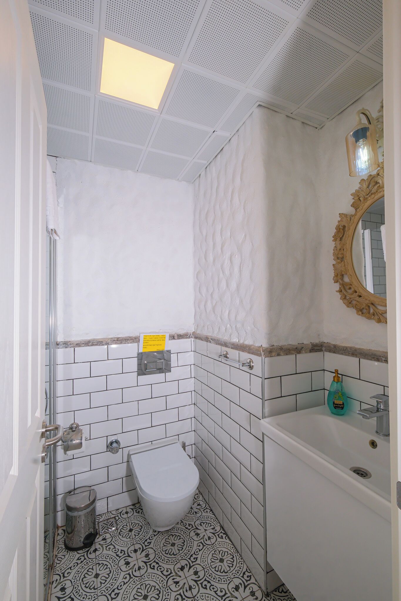 A bathroom with a toilet, sink, and mirror.