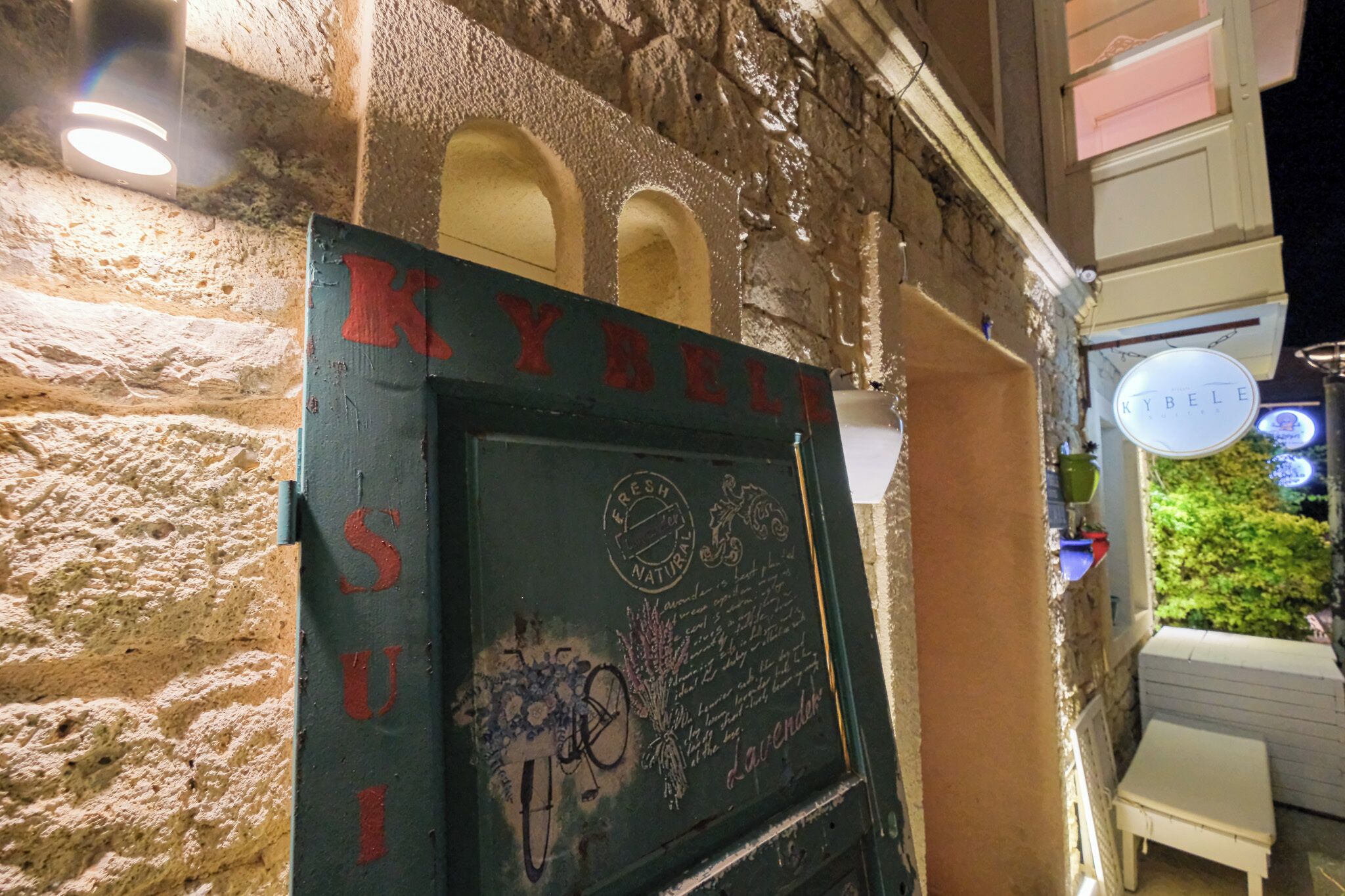 A stone wall with a sign reading "KYBELLE" and a chalkboard with text and drawings.