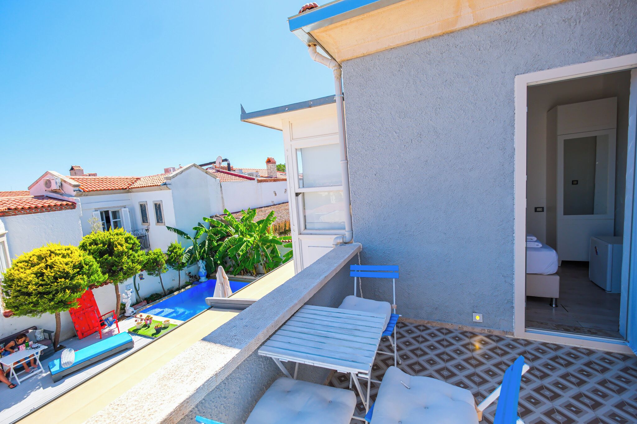 A rooftop terrace with a pool, outdoor seating, and a view of neighboring buildings.