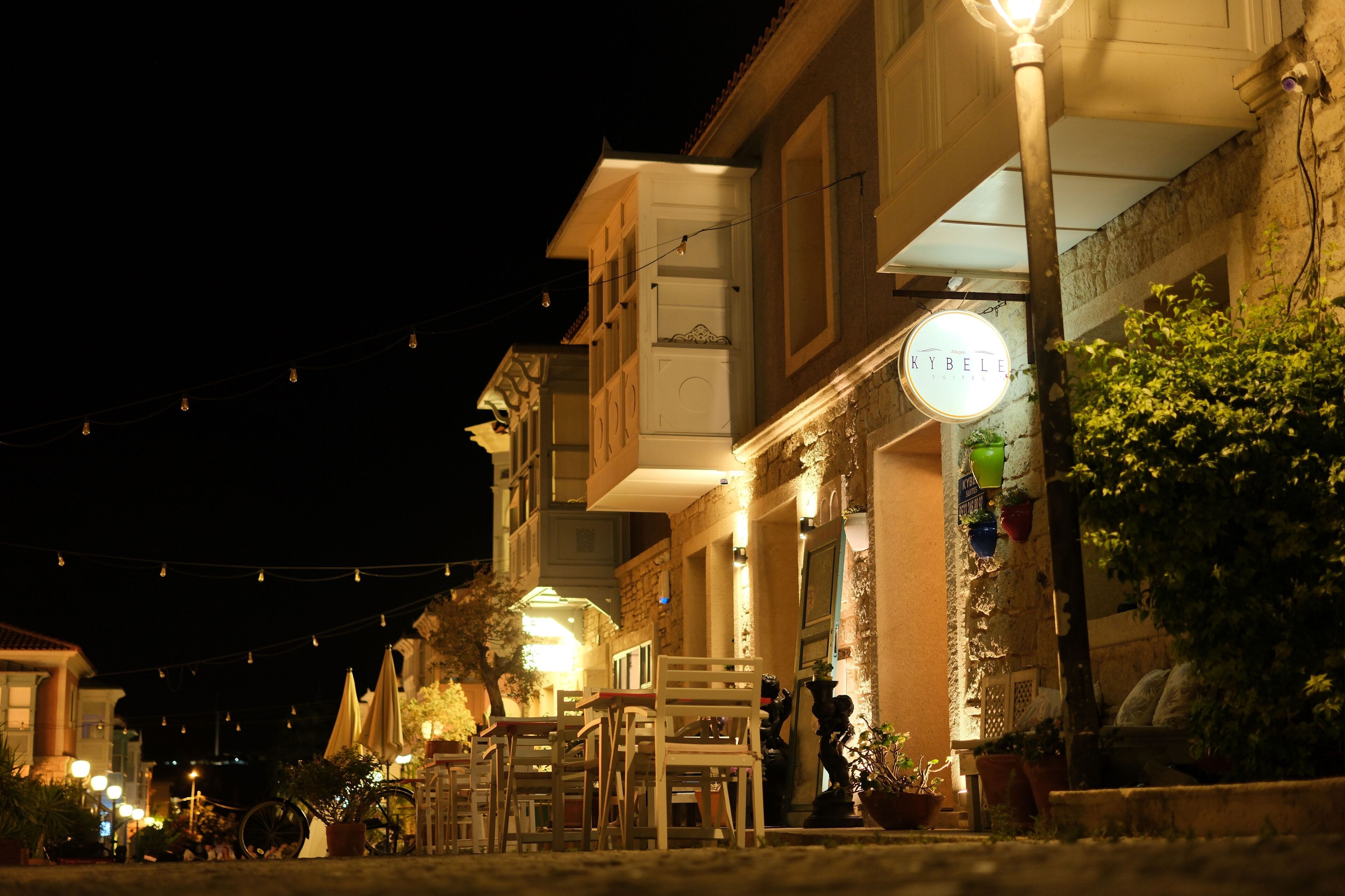 A street at night with outdoor seating and a sign for a restaurant.