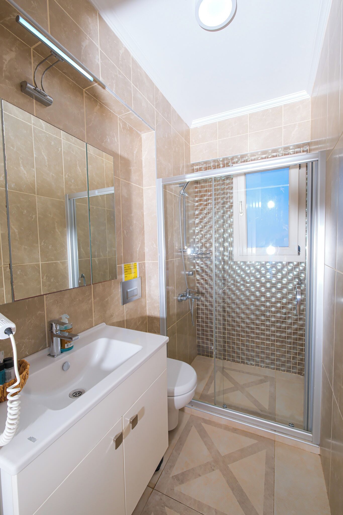 A bathroom with a glass shower enclosure, a white sink, and a mirror.