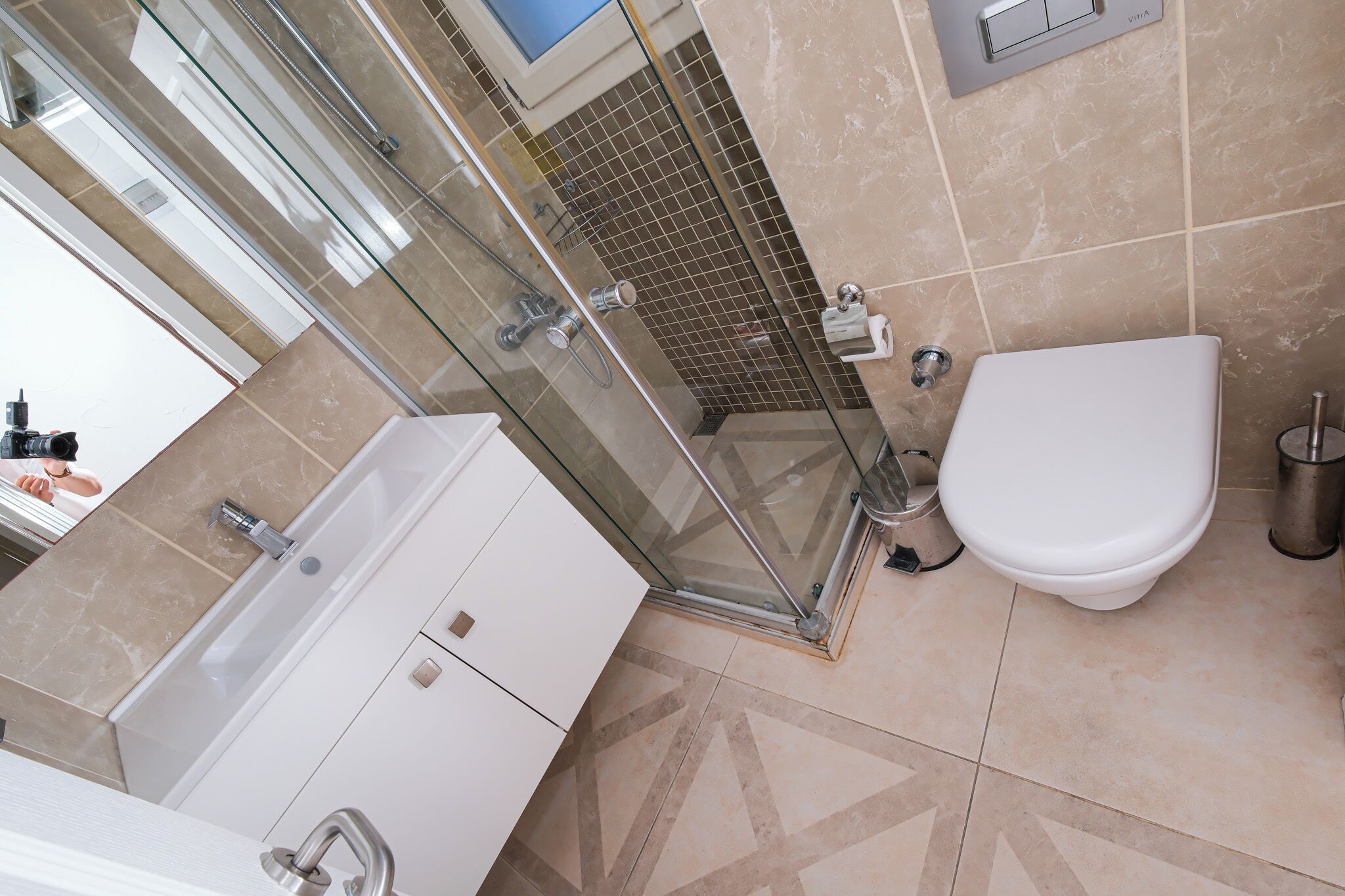Un baño moderno con cabina de ducha de vidrio, inodoro y lavabo con tocador.