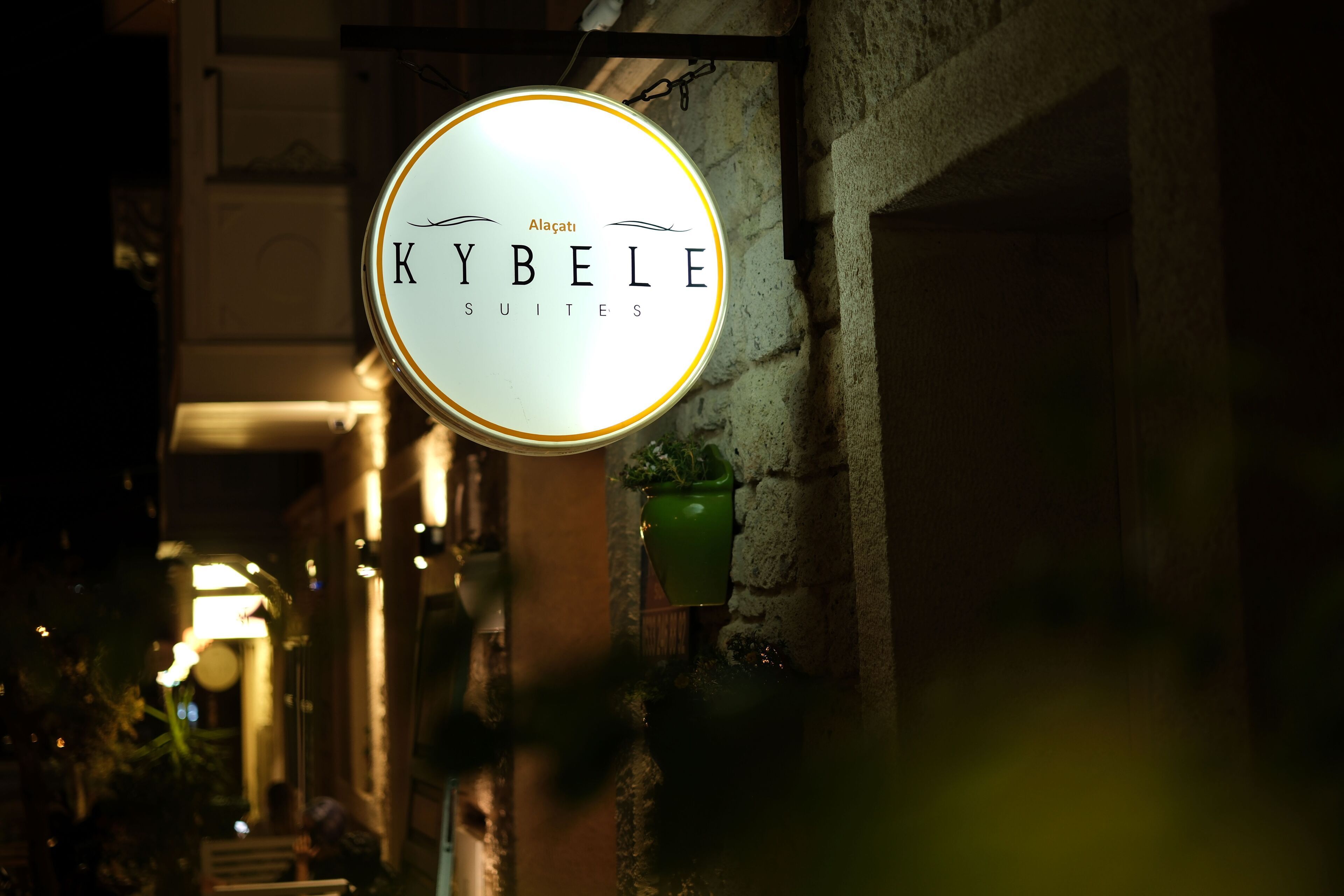 A sign for 'Kybelle Suites' in a dimly lit alleyway.