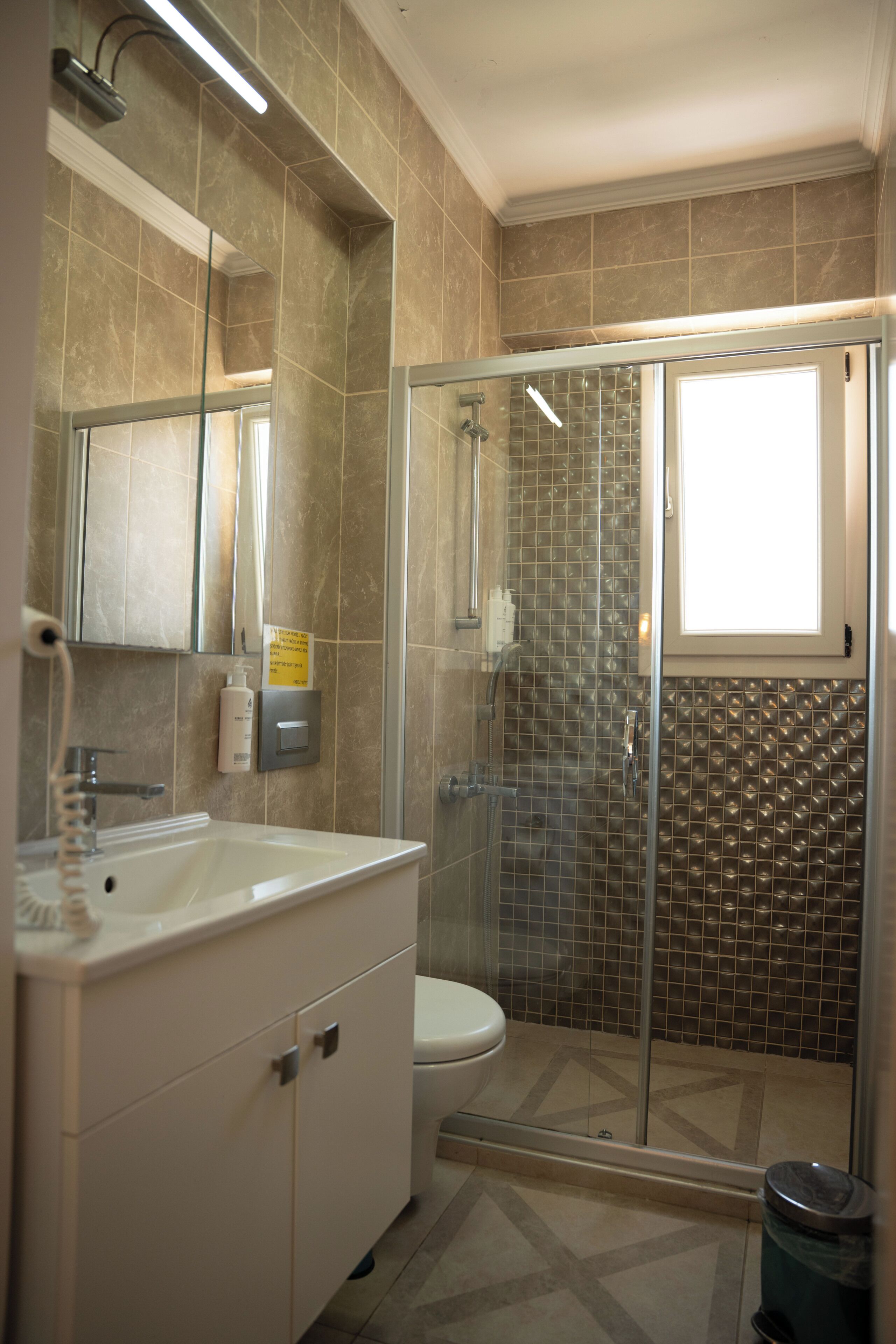 Un baño con ducha de vidrio, lavamanos con espejo y retrete.