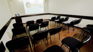 A conference room with a projector screen displaying 'Maranata Hotel' logo, arranged chairs, and a podium. - Hotel Maranatá (Valledupar)