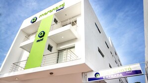 A modern hotel building with a prominent green vertical sign and a balcony on the second floor. - Hotel Maranatá (Valledupar)