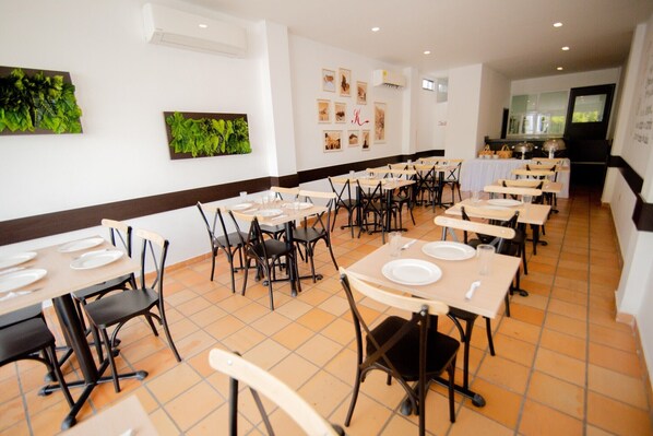 A dining area with multiple tables and chairs, arranged in rows.