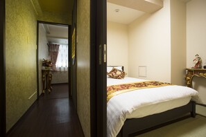 A hotel room with a bed, a nightstand, and a door leading to another room.