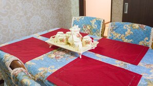 Una mesa ordenada con mantel floral, posavasos rojos y juego de té.
