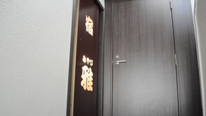 Una puerta de madera oscura con un pequeño ventanal y un letrero con caracteres japoneses.