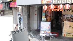 Fachada con letreros en japonés, una bicicleta y un cartel publicitario de comida.