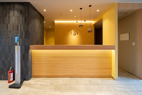 A reception desk with a digital screen, a fire extinguisher, and a wooden counter.