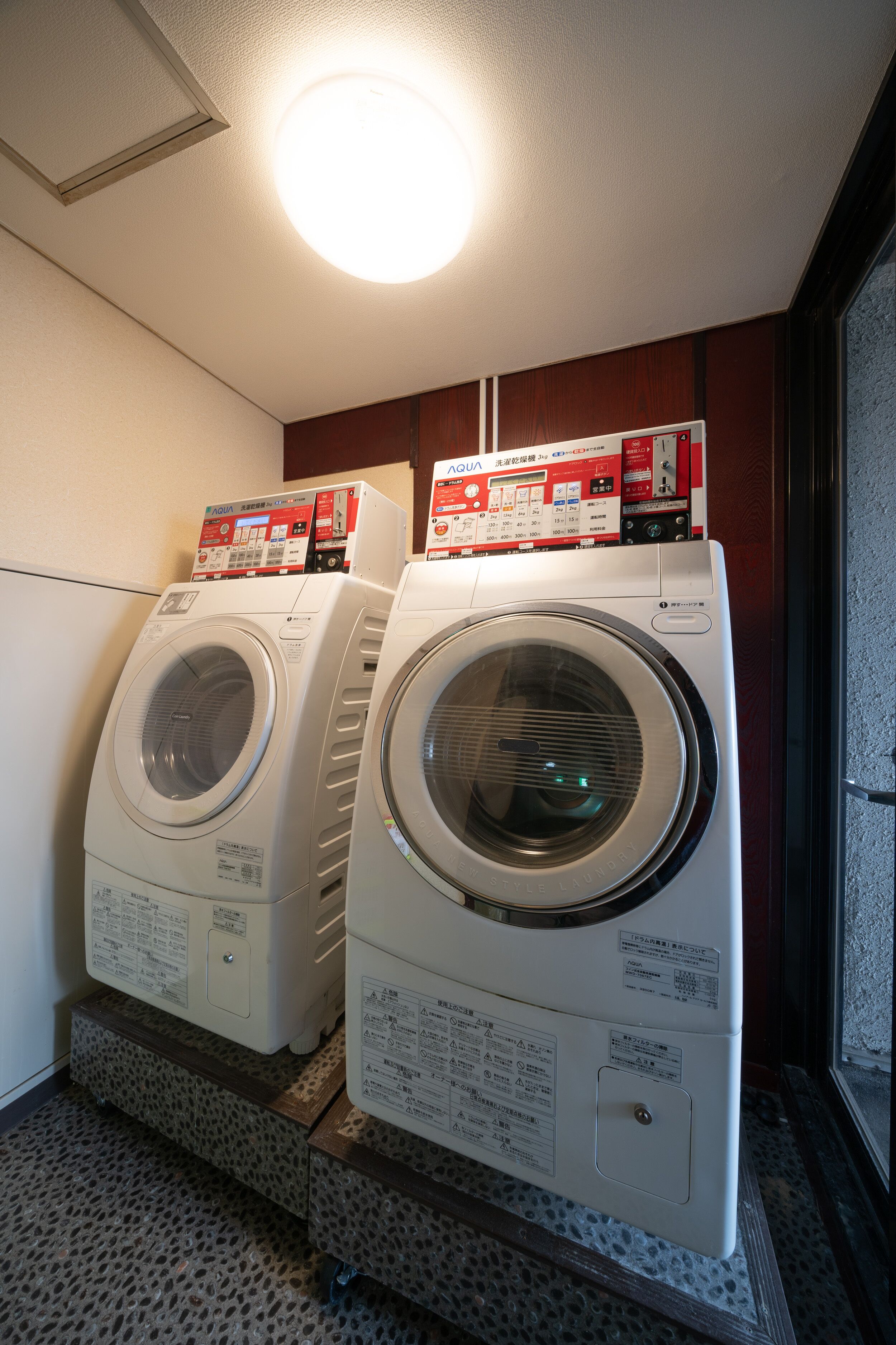 Two front-loading washing machines stacked on a platform with a wooden floor.