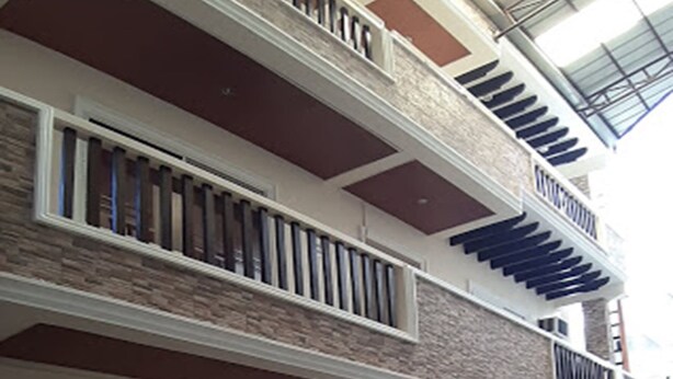 Edifici de dues plantes amb un balcó al pis superior, zona d'estar exterior coberta amb taula i cadires, i un carruatge de fusta estacionat a l'exterior.