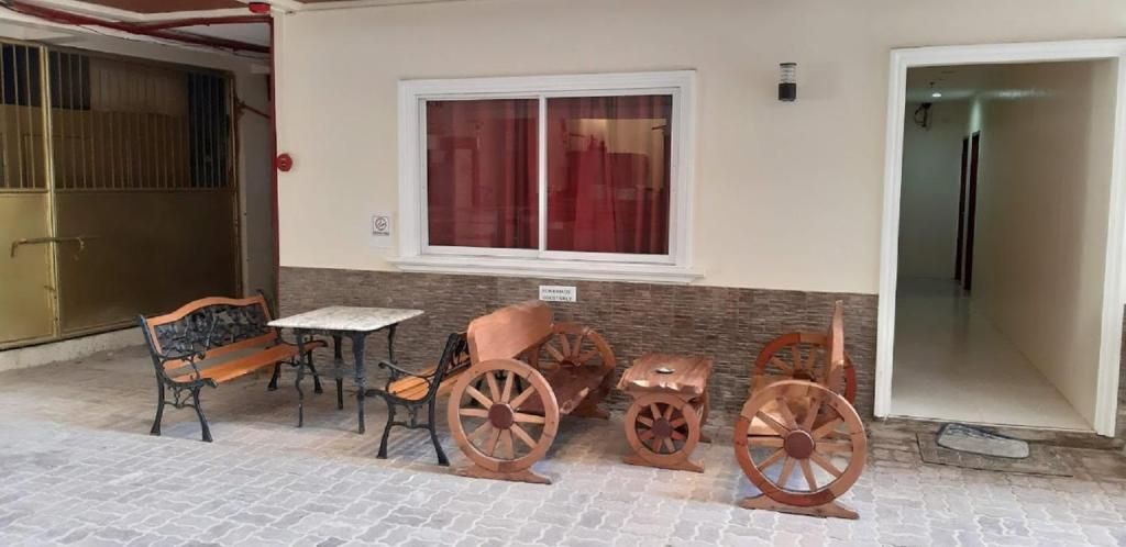 A covered outdoor seating area with a bench, table, and vintage-style wheels.