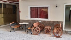 A covered outdoor seating area with a bench, table, and vintage-style wheels. - Eriko's House (Boracay Island)