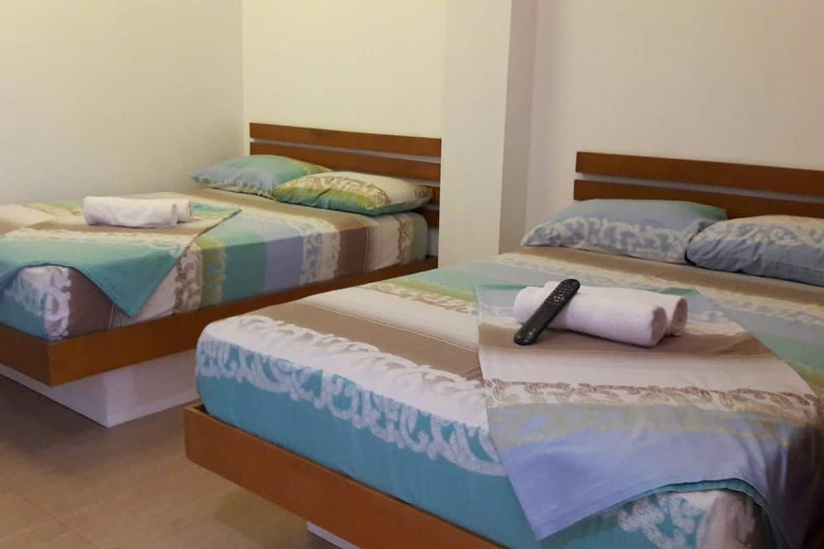 Dos camas individuales con cabeceros de madera, cada una con colcha y almohadas de diseño azul y blanco.