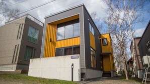 Un edificio moderno con fachada de ladrillo y madera, ventanas amplias y una entrada visible.