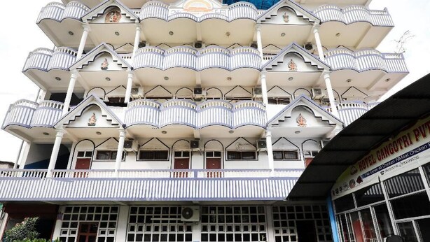 A multi-story building with balconies and a sign indicating it is a hotel.